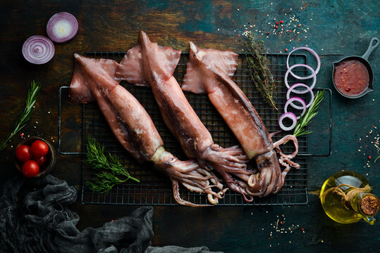 Fresh squid with spices on a dark stone background. On a dark background.