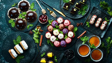 Set of sweets and desserts for coffee and tea on a black stone background. Top view. Rustic style.