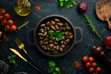 Fried chicken hearts with parsley and spices in a metal pan. Top view. Free space for text.