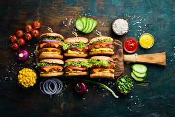 Homemade hamburger with fresh vegetables, meat and cheese. Top view. On a black stone background.