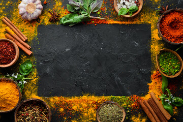 Colorful herbs and spices for cooking. Indian spices. On a black stone background. Top view. - obrazy, fototapety, plakaty