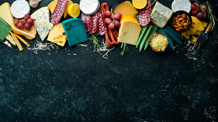 Set of colored cheese, sausages, salami and snacks. On a dark background. Free copy space. Top view.