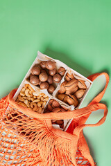 Flat lay Mesh grocery shopping eco friendly bag Assorted nuts on green canvas background, Zero waste cconcept, Local farmers market, shopping mall, top view, copy space, Plastic free items.