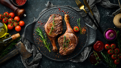 Baked duck thigh with spices and rosemary. Barbecue meat. Top view. Flat lay top view on black...
