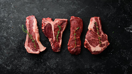 Variety of raw black Angus Prime meat steaks: t-bone, striploin, Rib eye, new york steak. Top view....