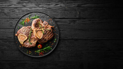 Obraz na płótnie Canvas Osso buco cooked Veal shank with spices and rosemary. Barbecue meat. Top view. Flat lay top view on black stone cutting table.