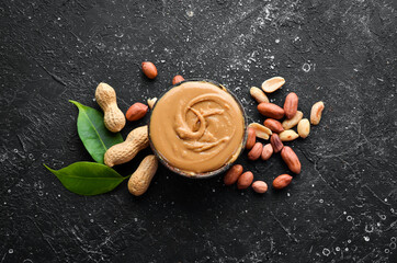 Peanut butter and nuts on a black stone background. Healthy food. Top view.