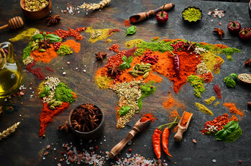 Spice banner. The map of the world is made of various spices and seasonings on a dark background. Top view. - obrazy, fototapety, plakaty