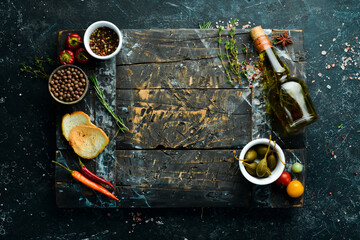 Wooden board on a black stone table with vegetables and spices. Food background. Top view. Rustic...