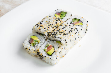 Traditional sushi rolls and maki with sesame, avocado and fish. Japanese food. Top view. On a white background.