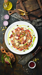 Salmon and tuna carpaccio with sauce and cheese on a white plate. Top view. Rustic style.