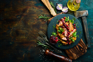 Fried chicken liver with cranberry sauce and cranberries on a black stone plate. Rustic style. Top view.