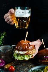 Street food. Homemade burger or burger with fresh vegetables and cheese. On a dark background.