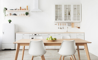 Light new kitchen furniture. Shelves with dishes, utensils, small refrigerator, chairs and table in scandinavian style