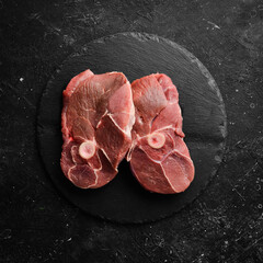 Meat. Lamb steak on the bone with rosemary and spices. On a black stone background. Top view.