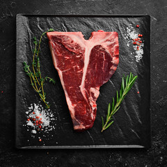Raw T-bone steak on a stone table with thyme, rosemary and spices. Top view. Flat lay top view on...
