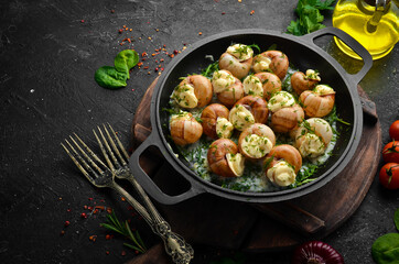 Bourgogne Escargot Snails with garlic, cheese in a creamy sauce on a black stone plate. Top view. Free space for text.