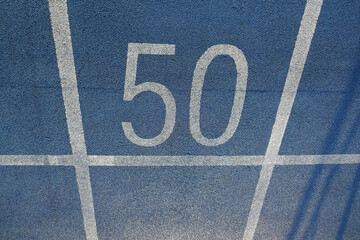 Close up of a blue running or jogging lane with white lines and number of fifty