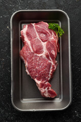 Fototapeta na wymiar Pork. Piece of raw fresh pork steak on black slate stone background. Top view. Cooking.