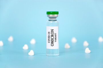New OMICRON variant of Coronavirus COVID-19 vaccine in glass vial with white heart shape tablets on...