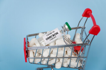 New OMICRON variant of Coronavirus COVID-19. Shopping cart with glass vial and pills. Supply and...