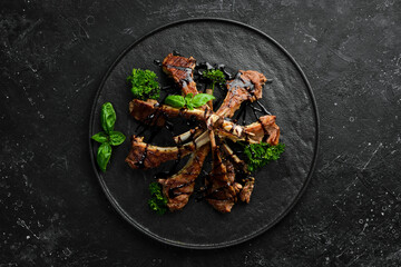 Roasted lamb ribs with spices and garlic on a dark kitchen table. Rustic style. Photo for the...