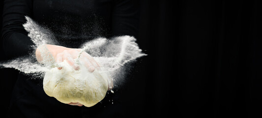 Fresh dough from wheat flour in hands. On a dark background. Cooking background.