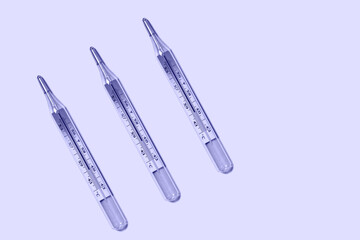 Three medical mercury thermometers in a row, close-up, flat lay. 2022 very peri color. Temperature is 39.9. 