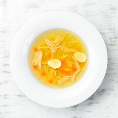 Quail soup. Quail meat broth with quail eggs and noodles. In a white plate. Top view.