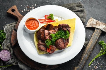 Juicy pork skewers with pita bread and sauce on a white plate. Top view.
