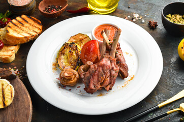 Baked lamb ribs with vegetables on a plate. Top view.