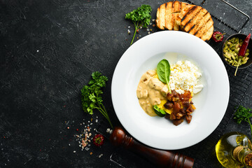 Ukrainian traditional cuisine. Banosh with mushrooms, bacon and brynza cheese on a plate. Top view.