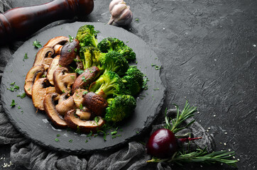 Organic food. Fried mushrooms and broccoli on a black stone plate. Rustic style. Top view.