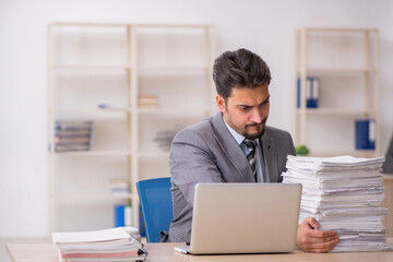 Young male employee unhappy with excessive work in the office