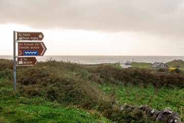 Sign Fanore beach and viewpoint on a metal fence. Popular travel destination on Wild Atlantic Way tourist route with amazing view on the ocean. Car park in the background. © mark_gusev