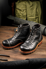 Hand crafted black leather high boots on wooden background