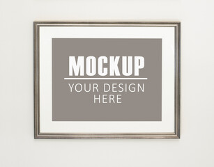 Frame, poster mock up. Empty silver picture frame hanging on the wall. Free space for your picture or text, copy space. Minimalist design.