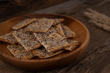 cereal cracker, rectangular bread or cookies with seeds and different seeds on a wooden background close-up
