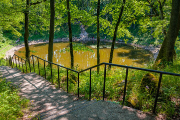 Stairs leading to the lake. Round lake in Kaali meteorite crater. Estonian island of Saaremaa.