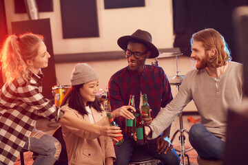 Multi-ethnic group of young people drinking beer while enjoying rehearsal in music studio