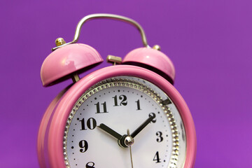 Alarm clock on an isolated minimalistic background in color 17-3938 very peri. Time to look for gifts for loved ones, time to celebrate. The holiday is coming soon. Meet the deadline.