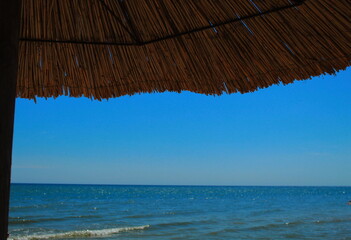Fototapeta na wymiar Reed umbrella by the sea 