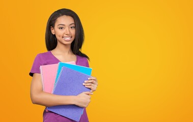 Obraz premium Smiling woman student with school books in hands on the background.