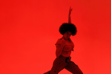 Young cool curly female dancer dancing hip hop
