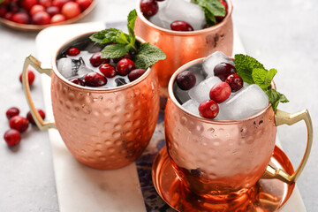Traditional american alcoholic beverage moscow mule in copper mugs with cranberry and mint on white marble board - non-alcoholic cocktail version
