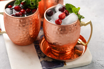 Traditional american alcoholic beverage moscow mule in copper mugs with cranberry and mint on white marble board - non-alcoholic cocktail version
