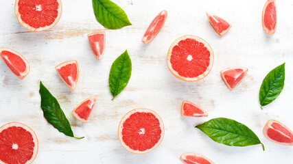 Fresh juicy grapefruit with leaves. Citrus fruits on white wooden background. Top view. Free copy space.