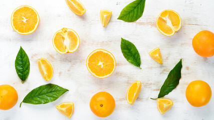 Fresh oranges with leaves. Citrus fruits on white wooden background. Top view. Free copy space.