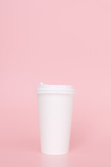 Take-out coffee with a white lid on top of a pink background.