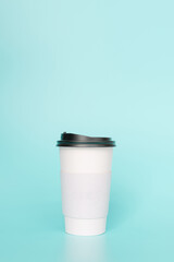 Take-out coffee with a black lid on top of the sky blue background.